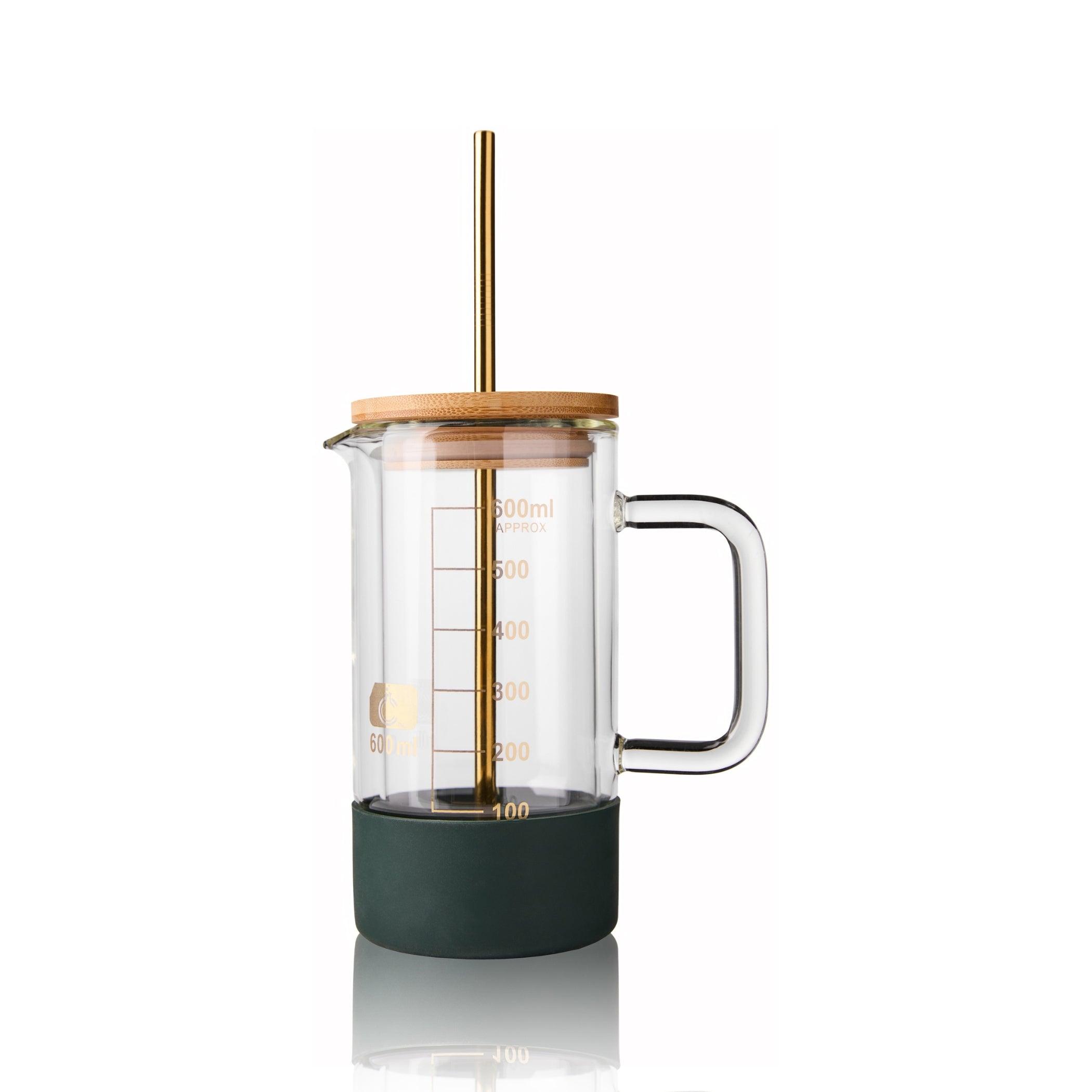 Elegant 600mL glass beaker tumbler with a bamboo lid, gold metal straw, and a dark green silicone base, combining scientific charm with modern drinkware functionality.