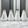 Four white bottles with engraved names on a marble surface